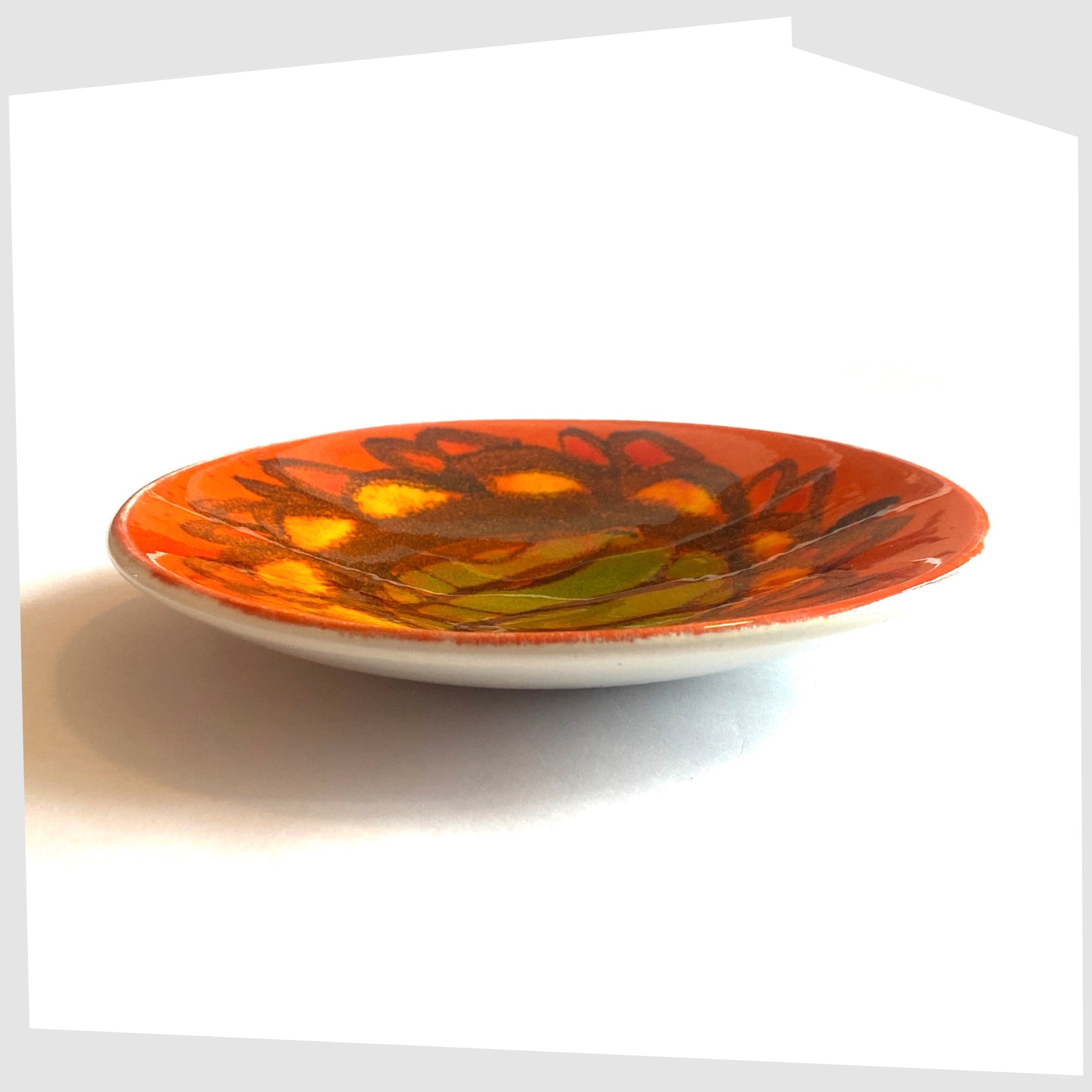 side of the Poole Pottery Pin Dish, shape 49 by Sylvia Penny, finished in a vivid Delphis glaze of vibrant orange, green and yellow