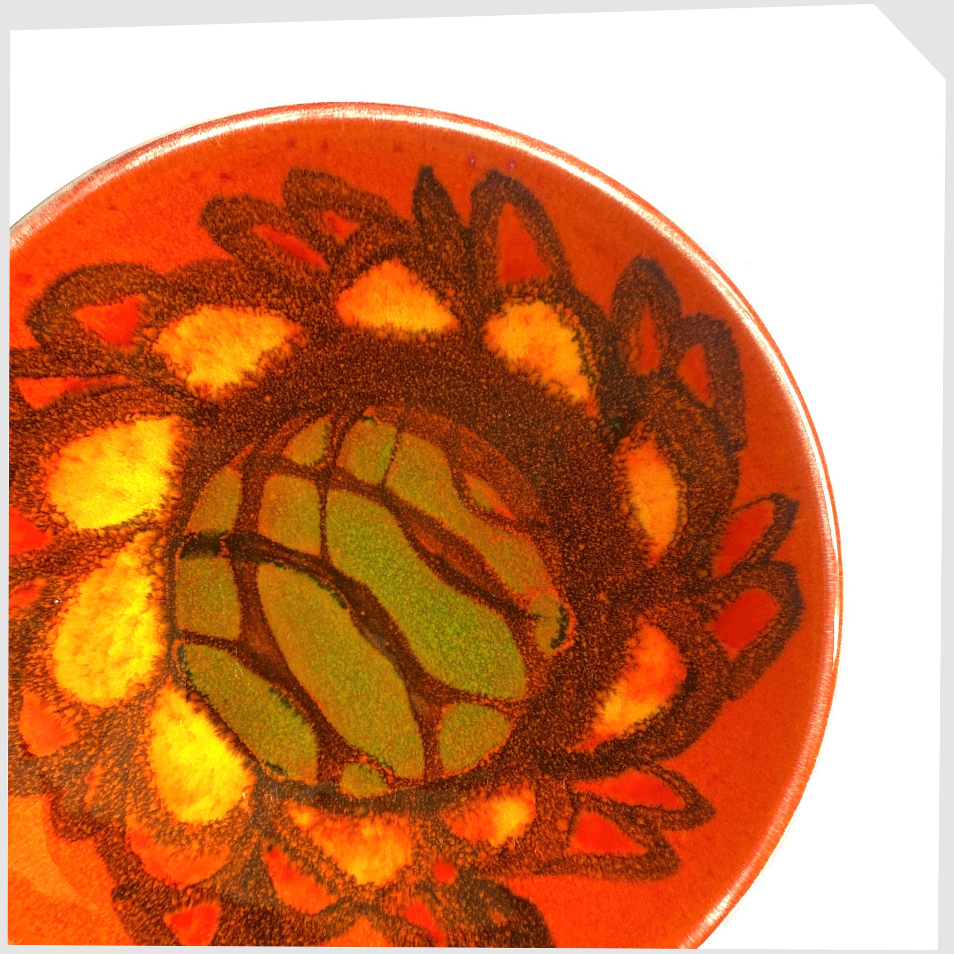 close up of the Poole Pottery Pin Dish, shape 49 by Sylvia Penny, finished in a vivid Delphis glaze of vibrant orange, green and yellow