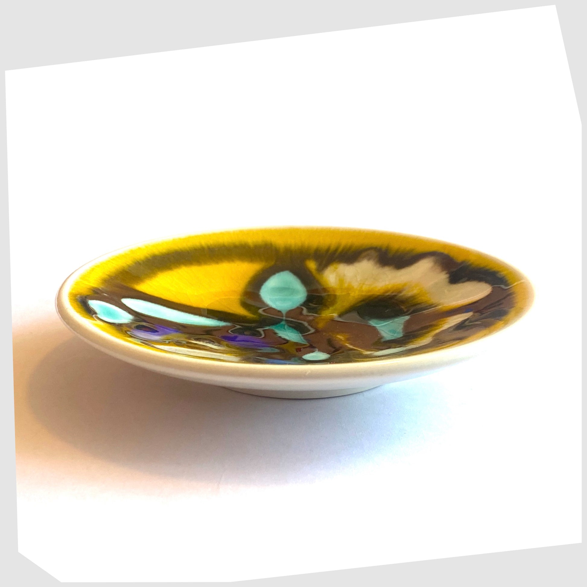 Side profile of the Poole Pottery Delphis Pin Dish, Shape 49, in a yellow glaze with fluid forms of turquoise and blue, created by Carol Cutler