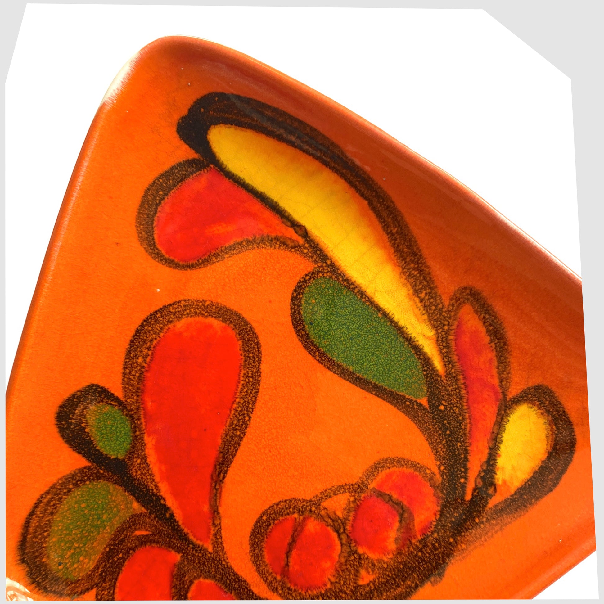close up of the glazing on the vintage Poole Pottery Delphis Dish, shape 81, by paintress Mary Albon in a vivid orange glaze with fluid forms of red, green and yellow