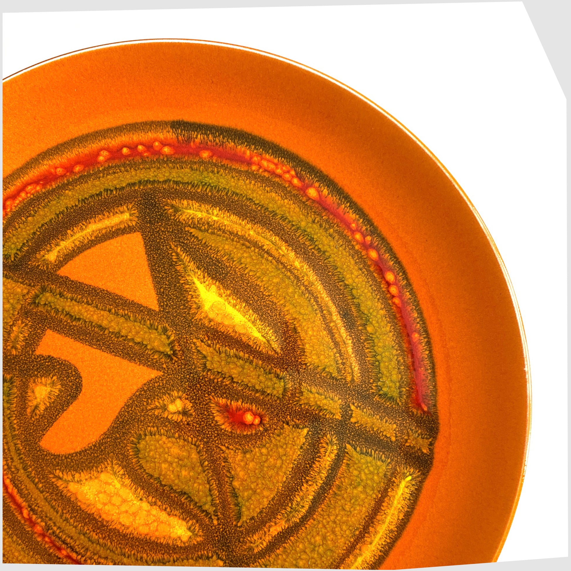 close up of the Poole Pottery Delphis Plate by Wendy Smith in a vibrant orange glaze with fluid forms of yellow and green