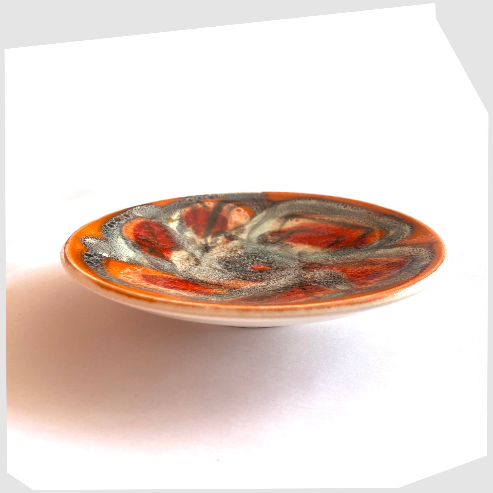 side profile of the Poole Pottery Delphis Pin Dish by Jean Millership finished in a vibrant orange, blue and red glaze