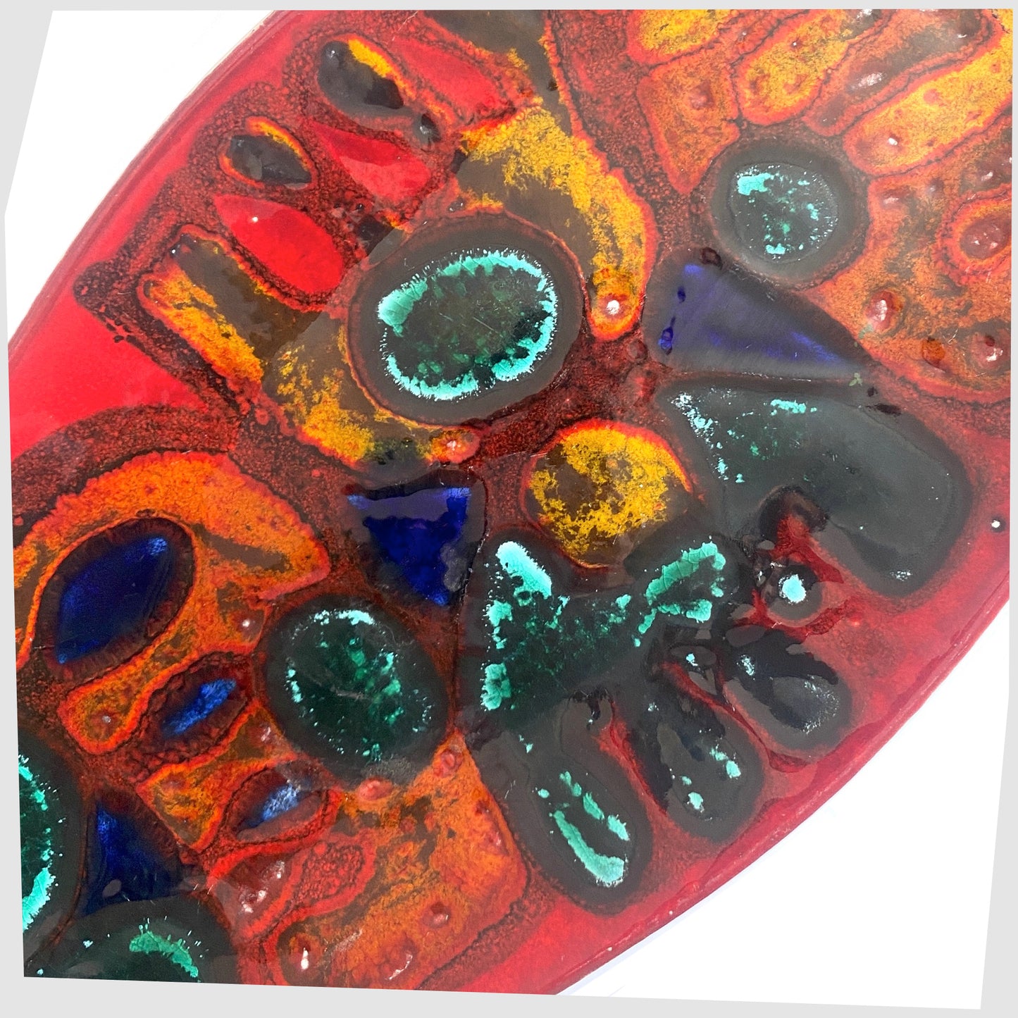 Close up of the Poole Pottery Delphis Spear Dish, Shape 82, by paintress Irene Kerton finished in a vibrant red glaze with fluid forms of orange and turquoise, shown on a white background