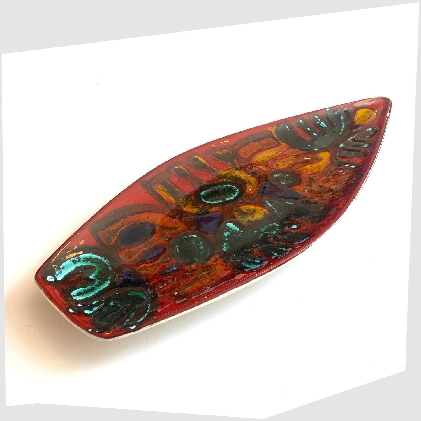 1960s Poole Pottery Delphis Spear Dish, Shape 82, by paintress Irene Kerton finished in a vibrant red glaze with fluid forms of orange and turquoise, shown on a white background