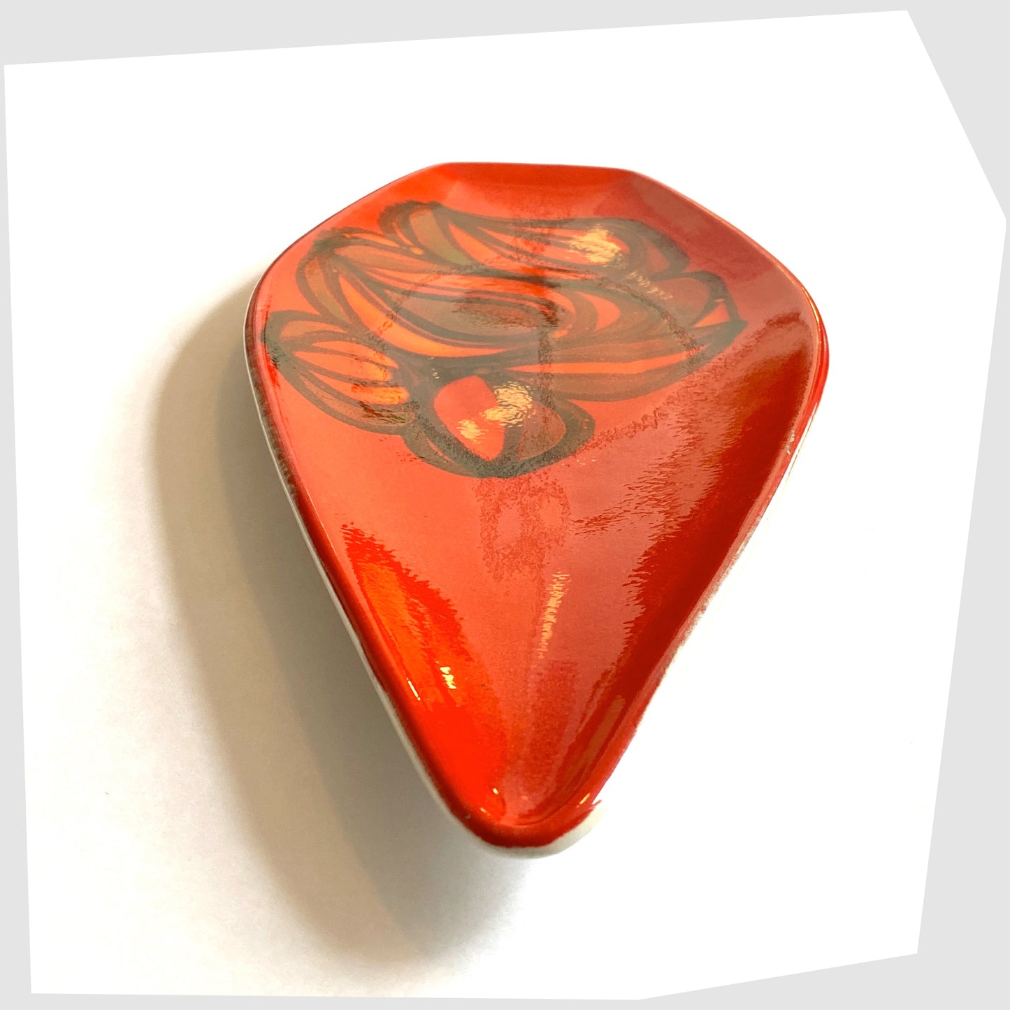 front tip of the Poole Pottery Spear Dish in a red Delphis glaze with free-form shapes in orange and green