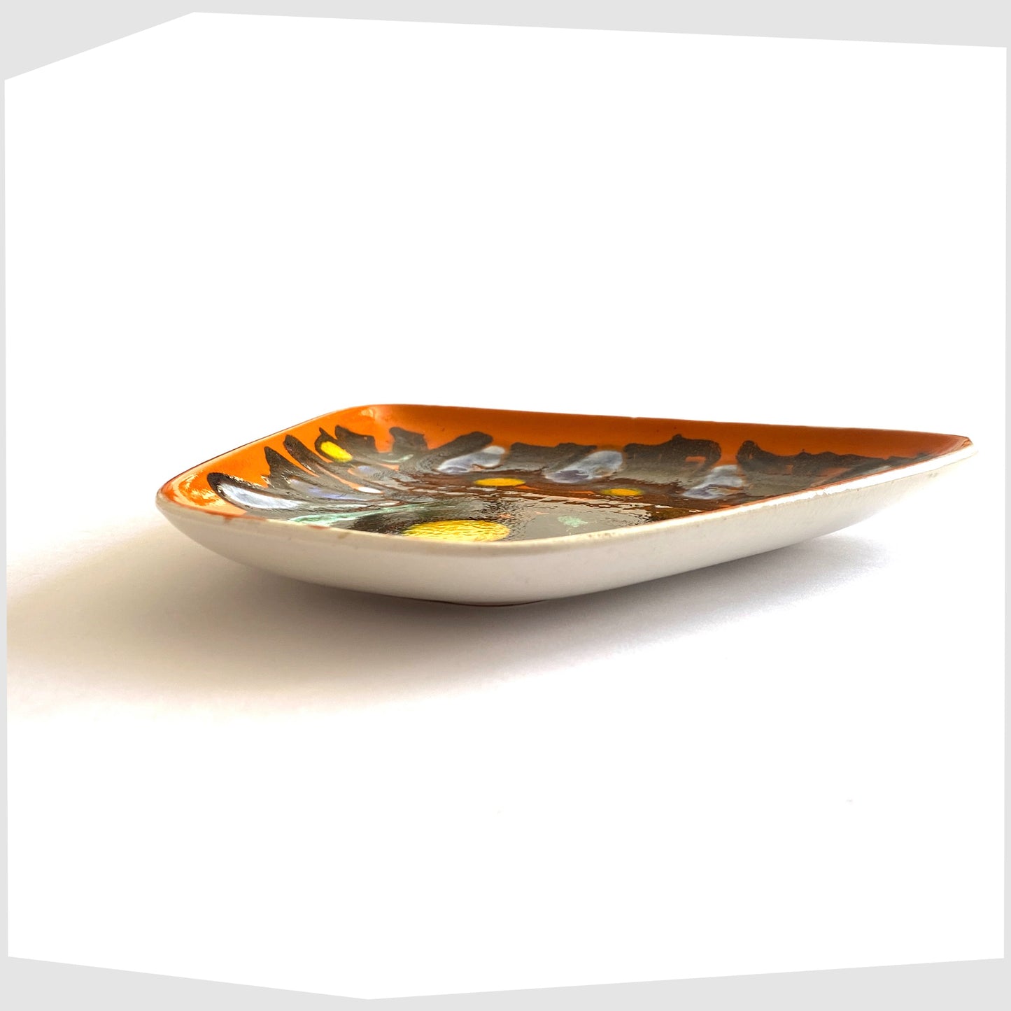 side profile of the poole pottery delphis dish, shape 81, glazed in a vibrant orange with black lines framing yellow and blue circles