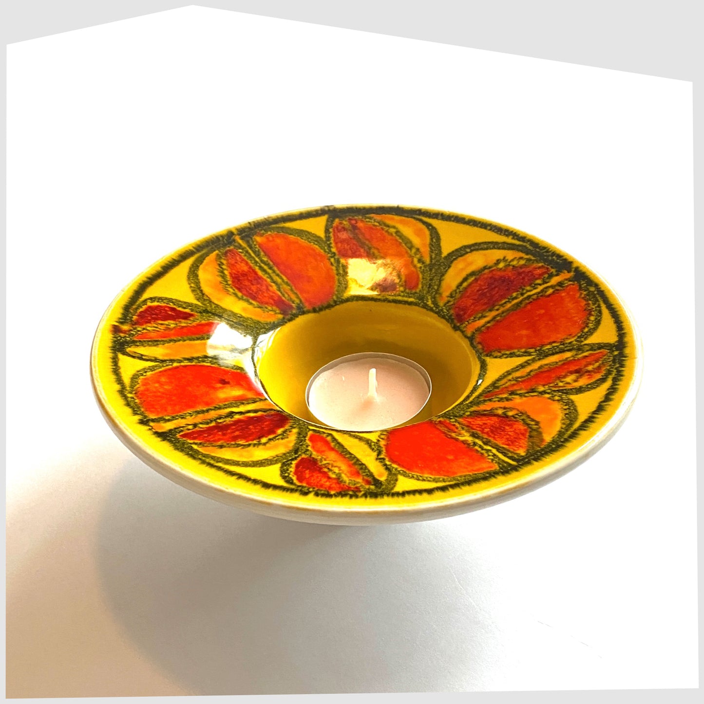 poole pottery delphis tealight candleholder in a vivid yellow with circular forms of red and orange glaze