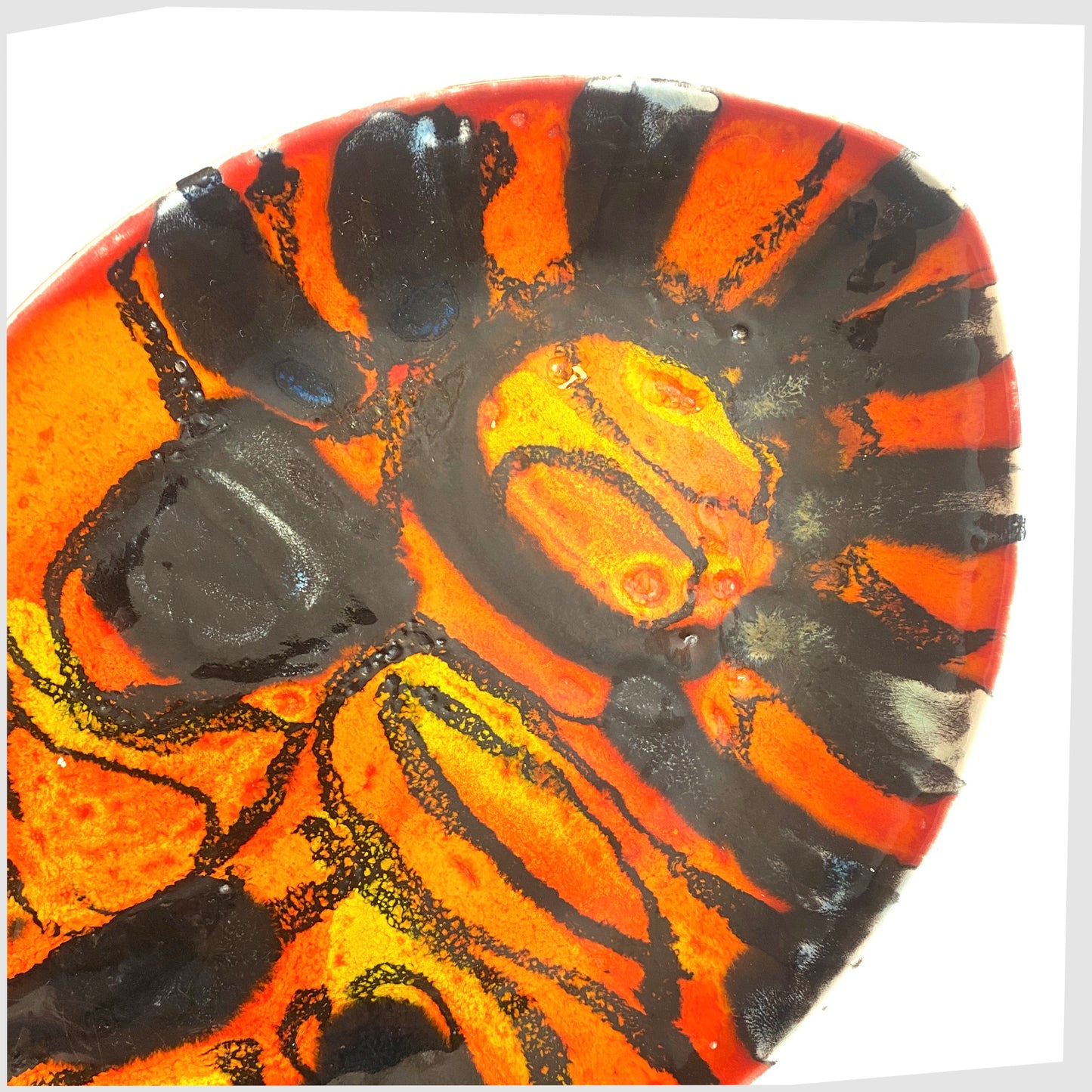 close up of the Poole Pottery Delphis Teardrop Dish in a unique glaze of vivid orange and red with contrasting forms of gloss black