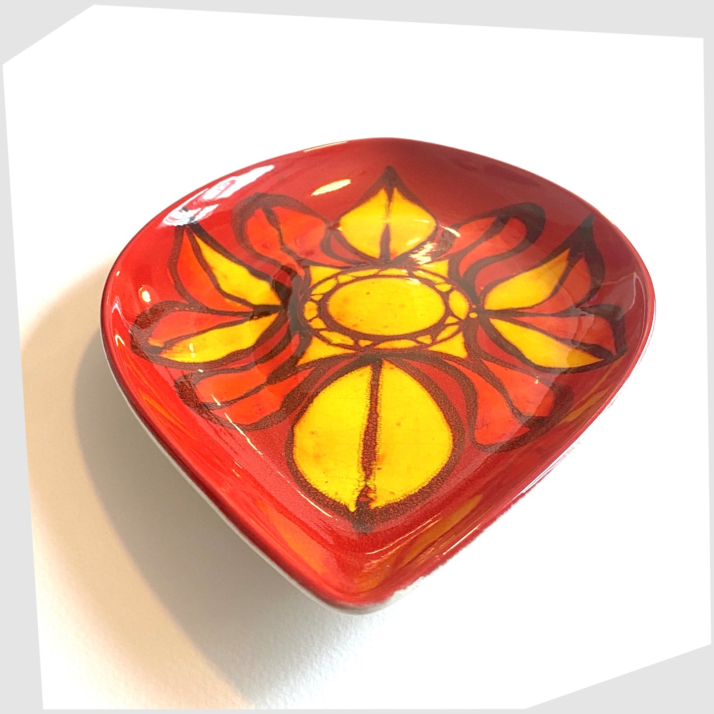 front angle of the Poole Pottery Delphis Teardrop dish in vivid red and yellow glaze, created by Janet Laird