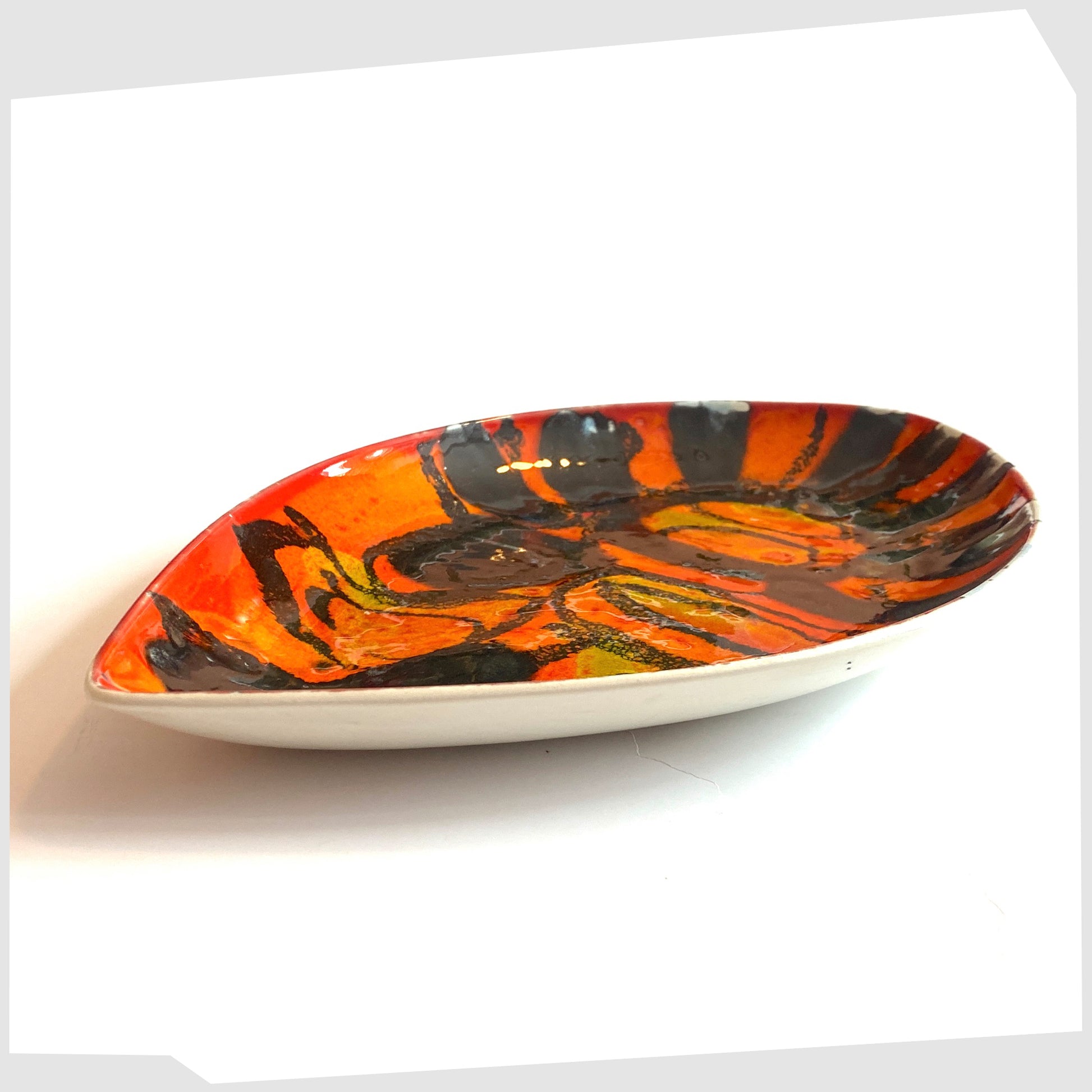 side profile of the Poole Pottery Delphis Teardrop Dish in a unique glaze of vivid orange and red with contrasting forms of gloss black
