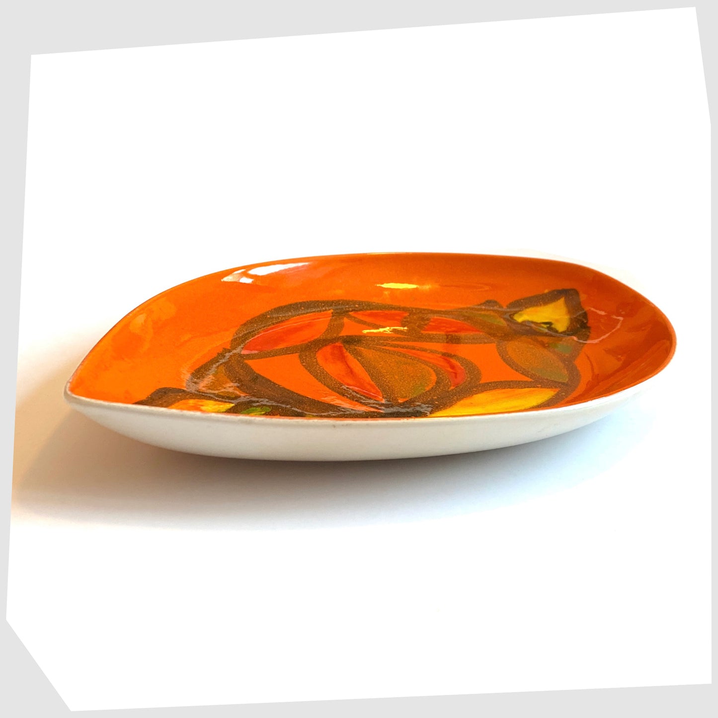side profile of the Poole Pottery Delphis Teardrop Dish by Anita Lawrence in an orange glaze with fluid forms of red, yellow and green