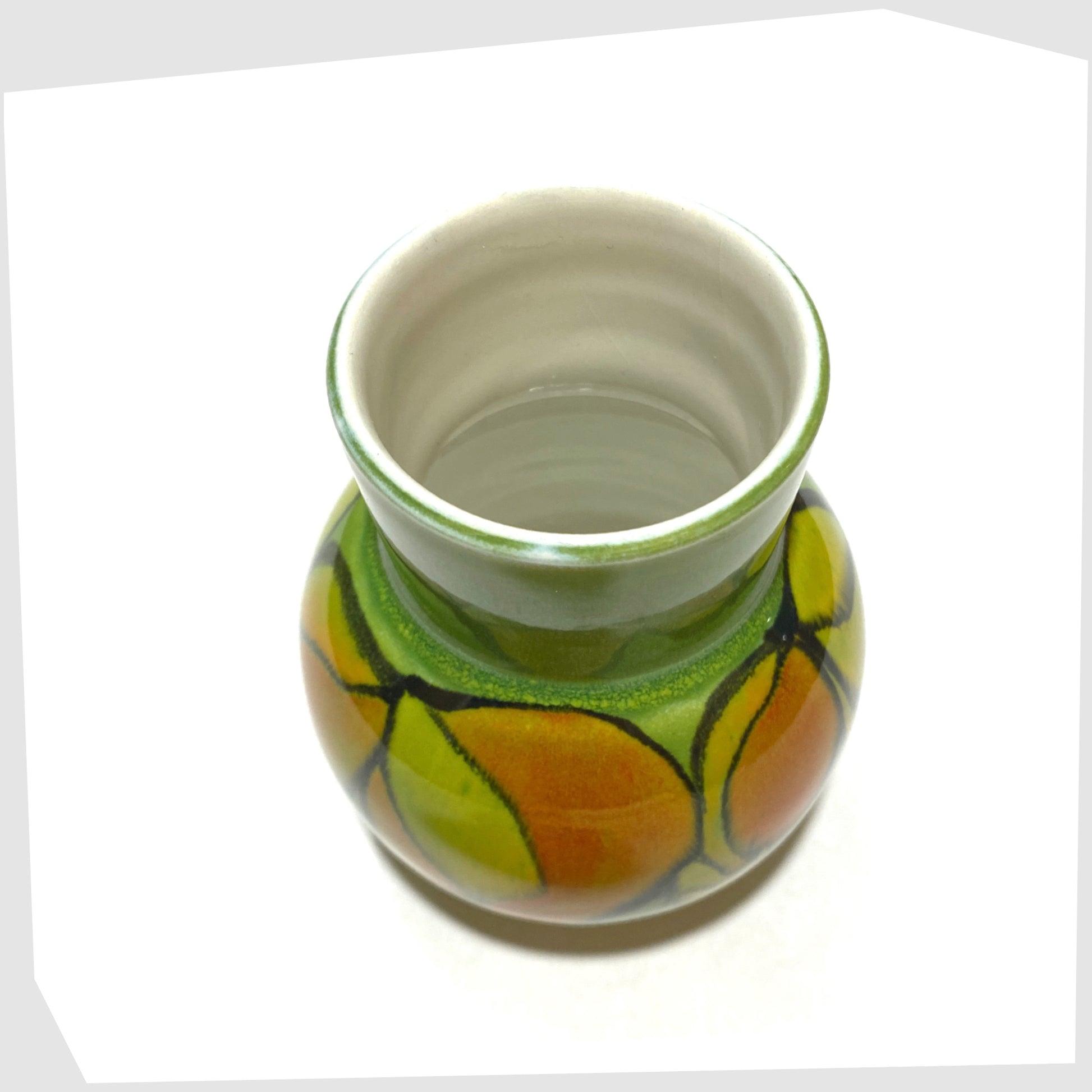 white inner glaze on the poole pottery vase, shape 31 by Julia Wills, finished in a green delphis glaze with yellow and orange forms