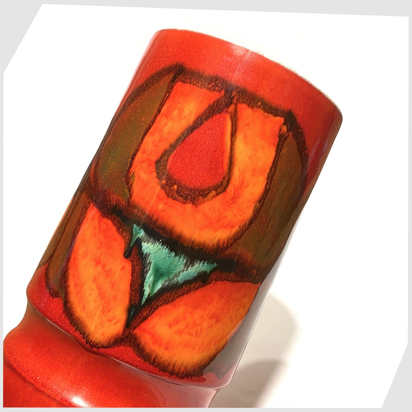 close up of the Poole Pottery cylinder vase, shape 84, in a red, green and orange Delphis glaze by Cynthia Bennett