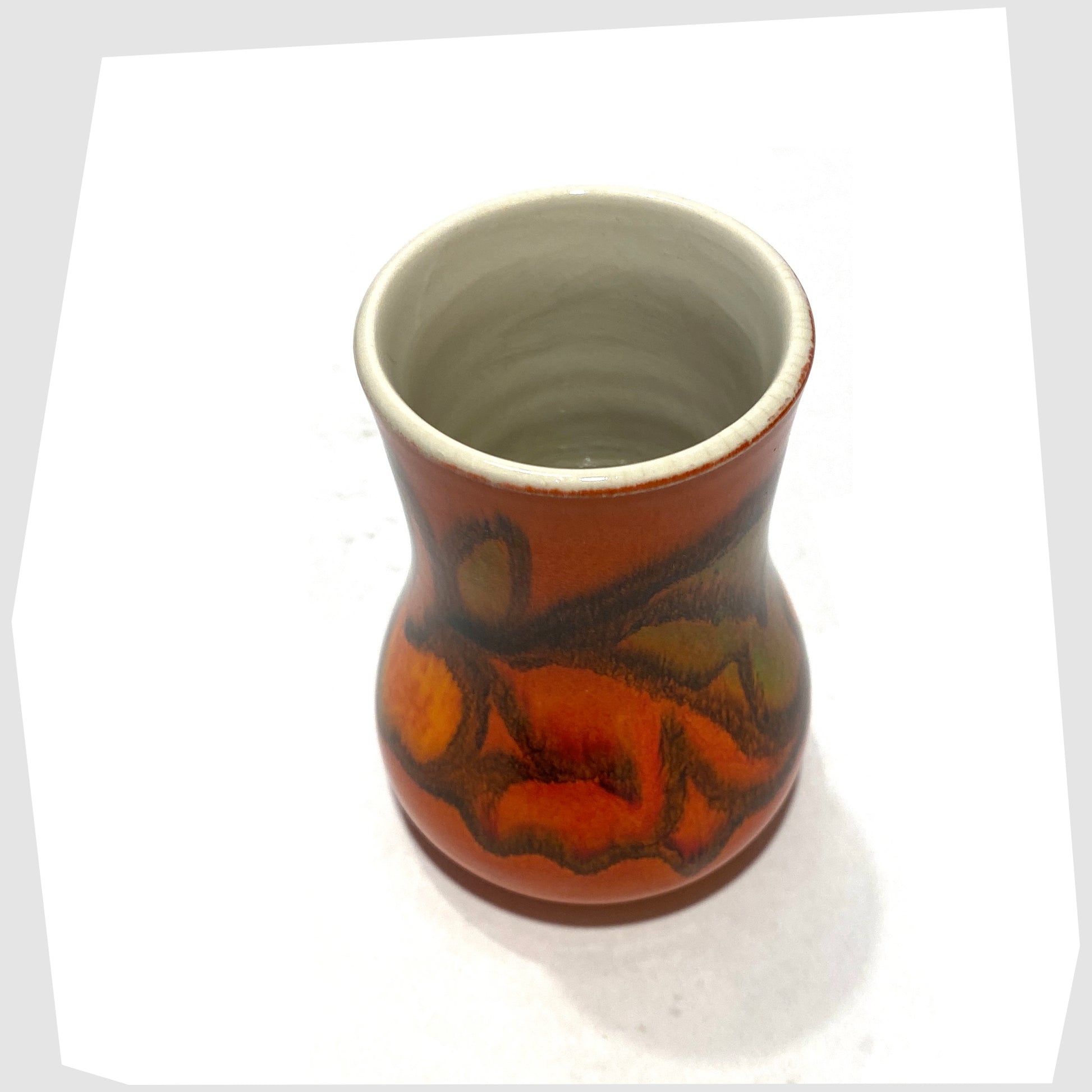 top rim of the compact Poole Pottery Delphis Vase, Shape 31, by Tina Fancy- glazed in a rich burnt orange with fluid forms of yellow, green and red, shown on a white background