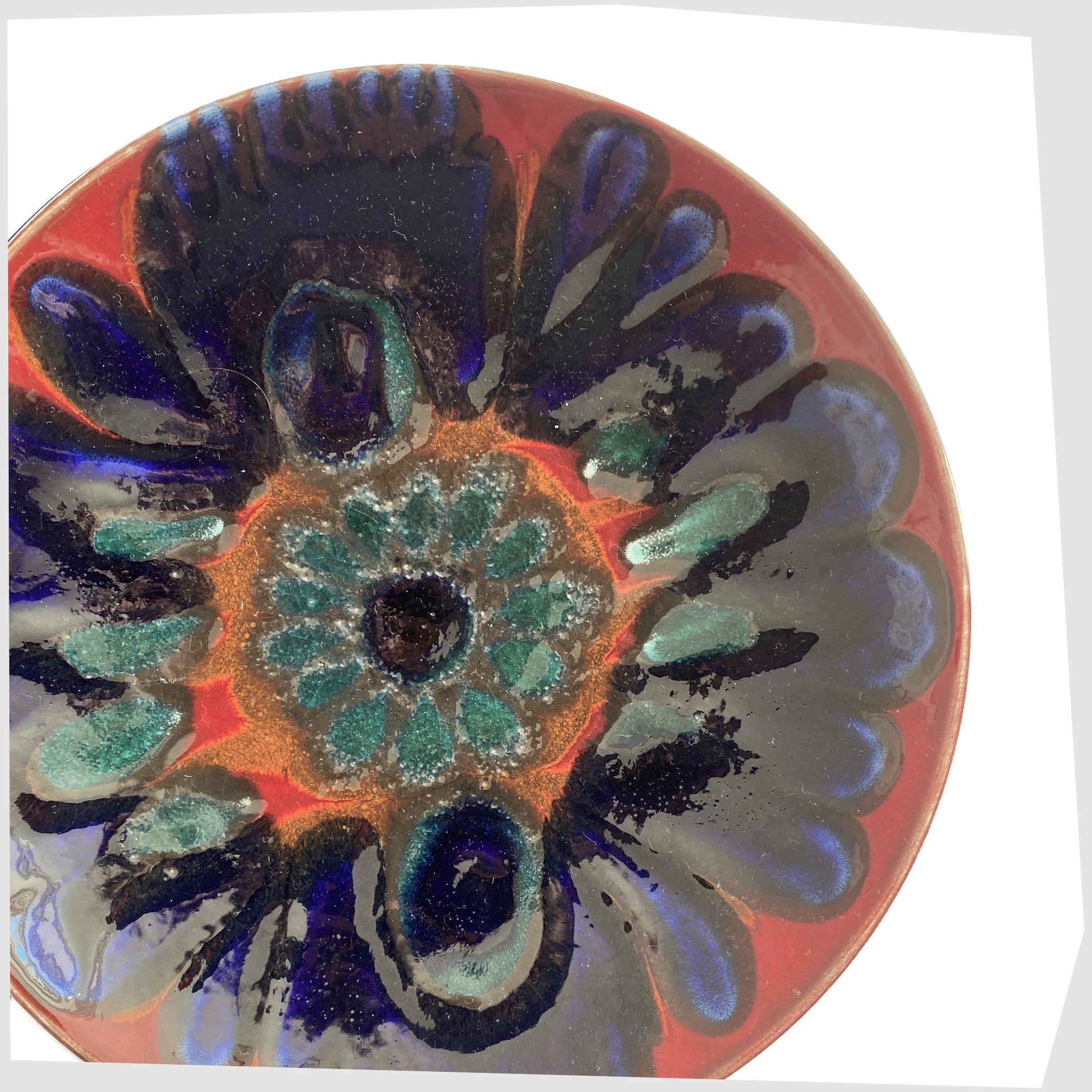 close up of the Poole Pottery Dish by Carloyn Bartlett glazed in a radiating design of red, cobalt blue and teal green