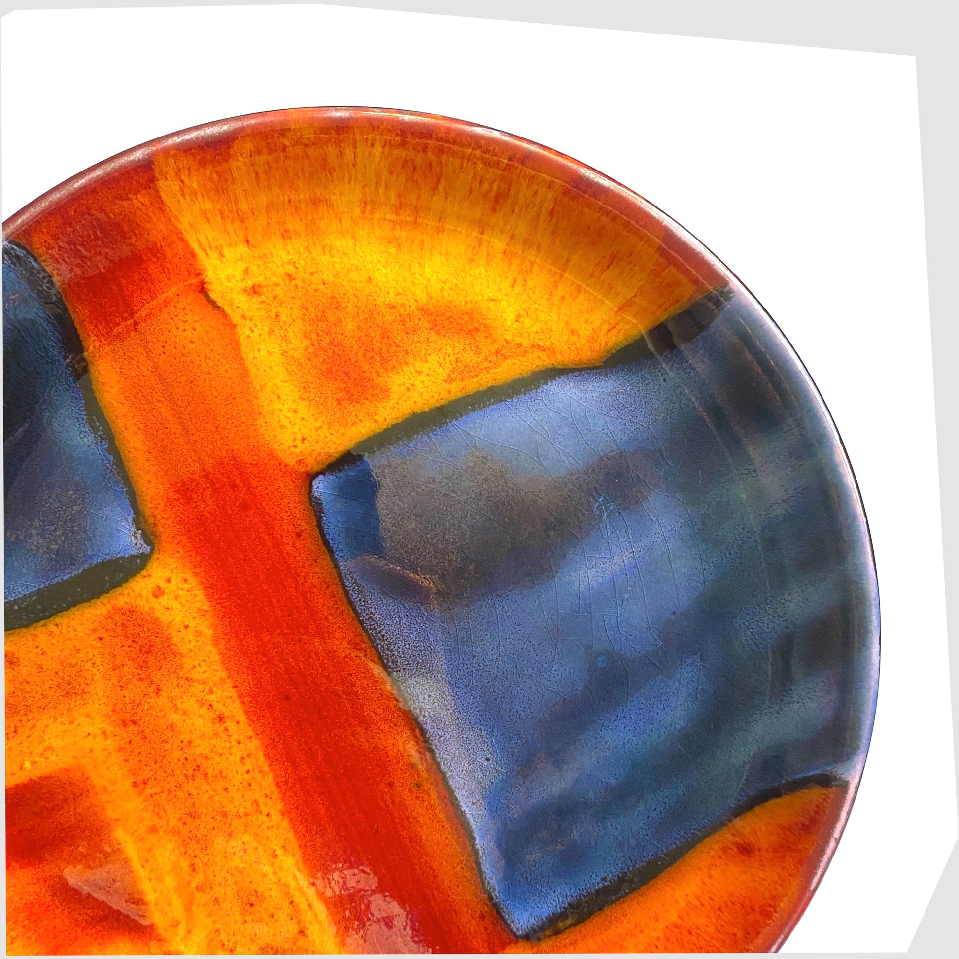 cloxe up of the poole pottery plate in gemstones glaze of rich orange, red and blue squares
