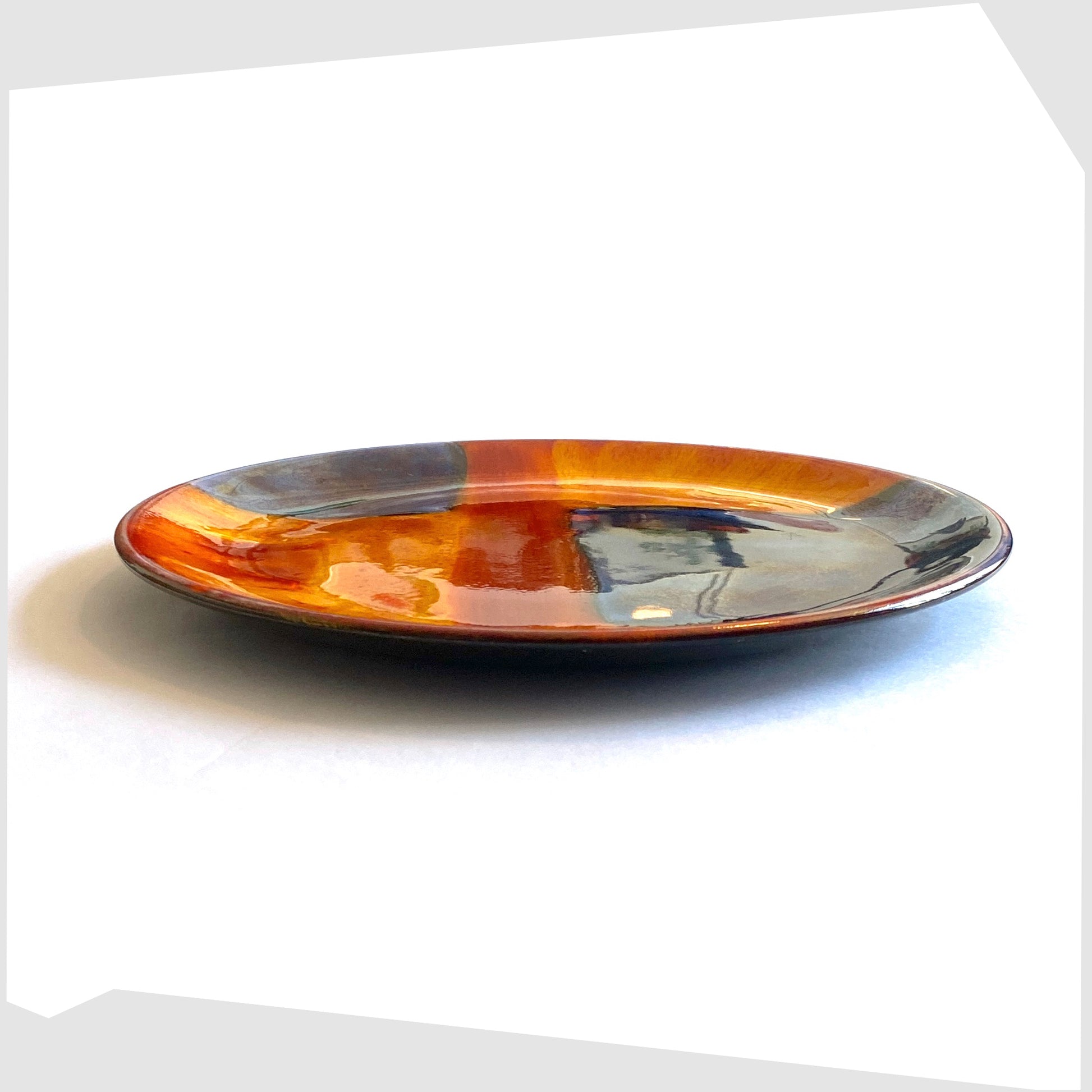 side profile of the poole pottery plate in gemstones glaze of rich orange, red and blue squares