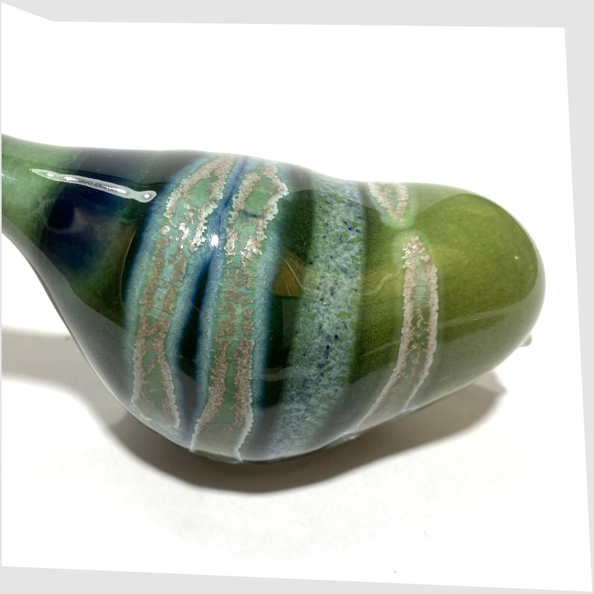 Close up of the Poole Pottery Pecking Bird Figurine in Maya glaze of green, blue and grey, shown on a white background