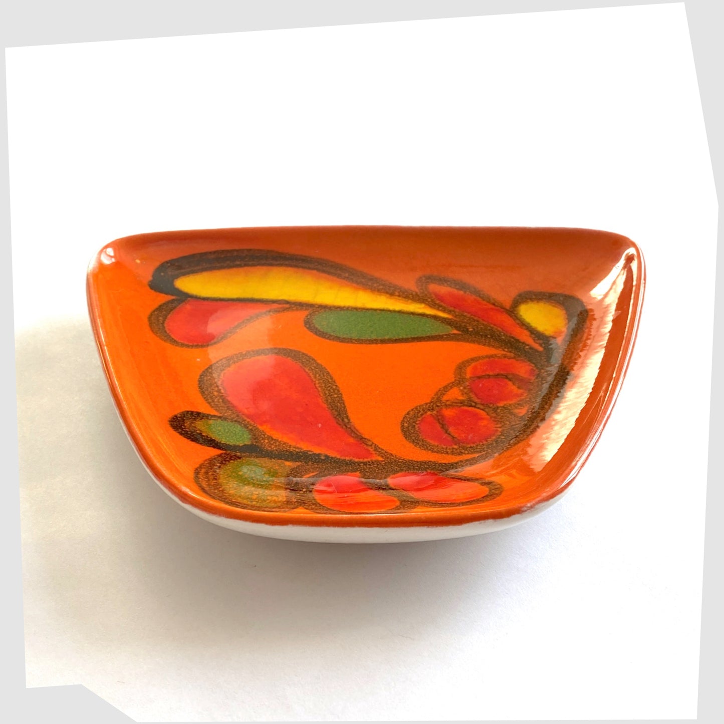 front edge of the Poole Pottery Delphis Dish, shape 81, by paintress Mary Albon in a vivid orange glaze with fluid forms of red, green and yellow