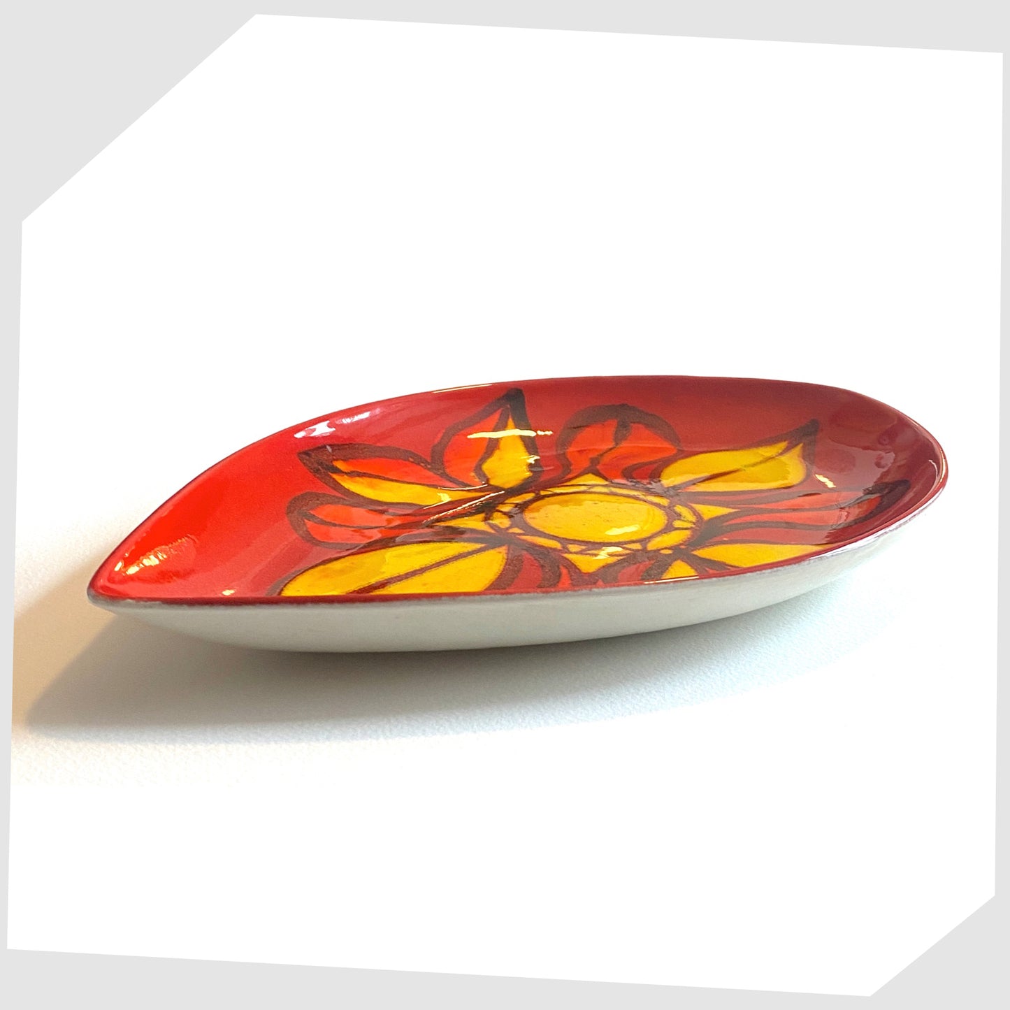 side profile of the Poole Pottery Delphis Teardrop dish in vivid red and yellow glaze, created by Janet Laird