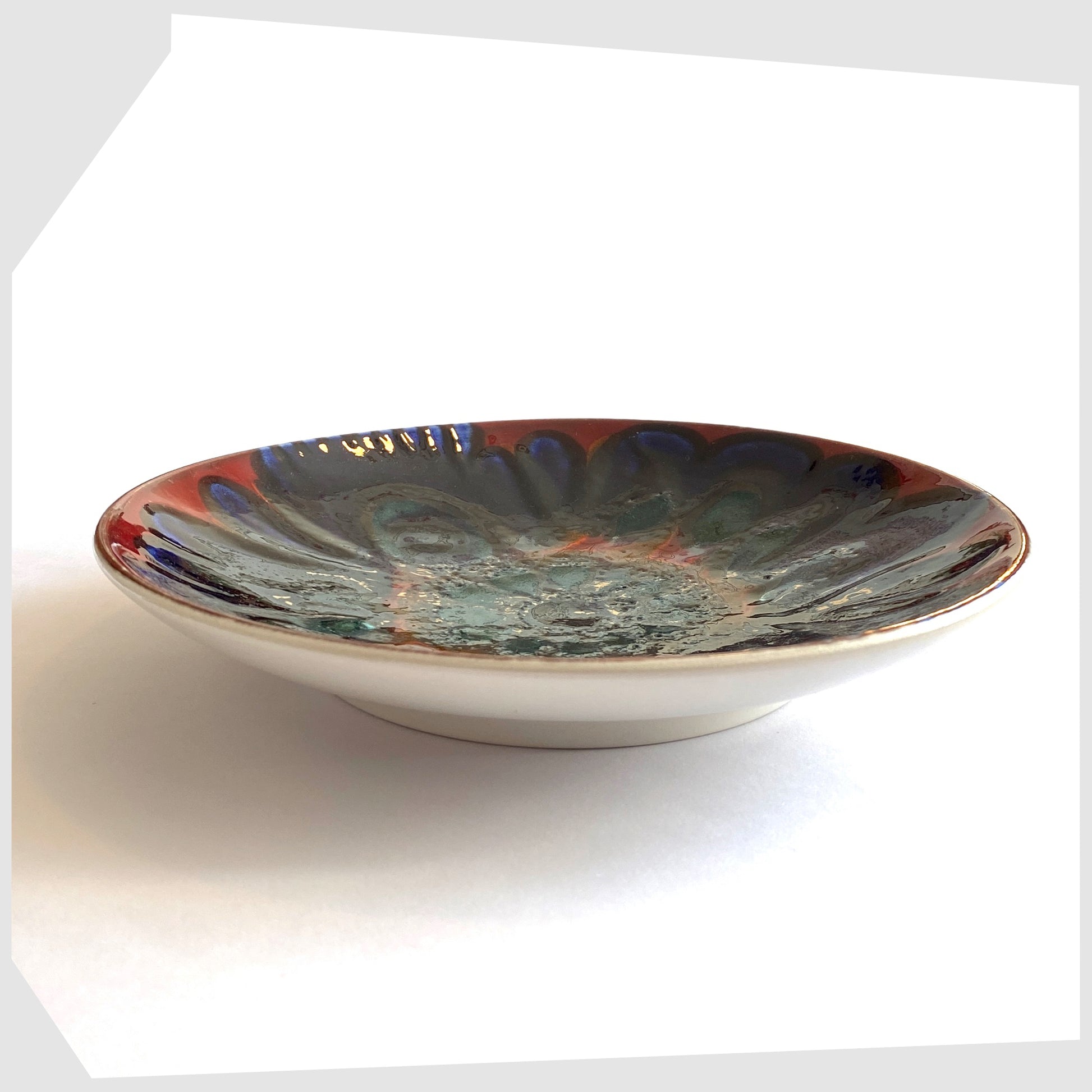 side profile of the Poole Pottery Shape 3 Dish by Carloyn Bartlett glazed in a radiating design of red, cobalt blue and teal green