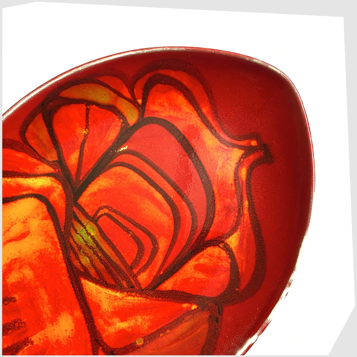 close up of the poole pottery delphis teardrop dish by Lynn Gregory, finished in a rich red with orange and green forms