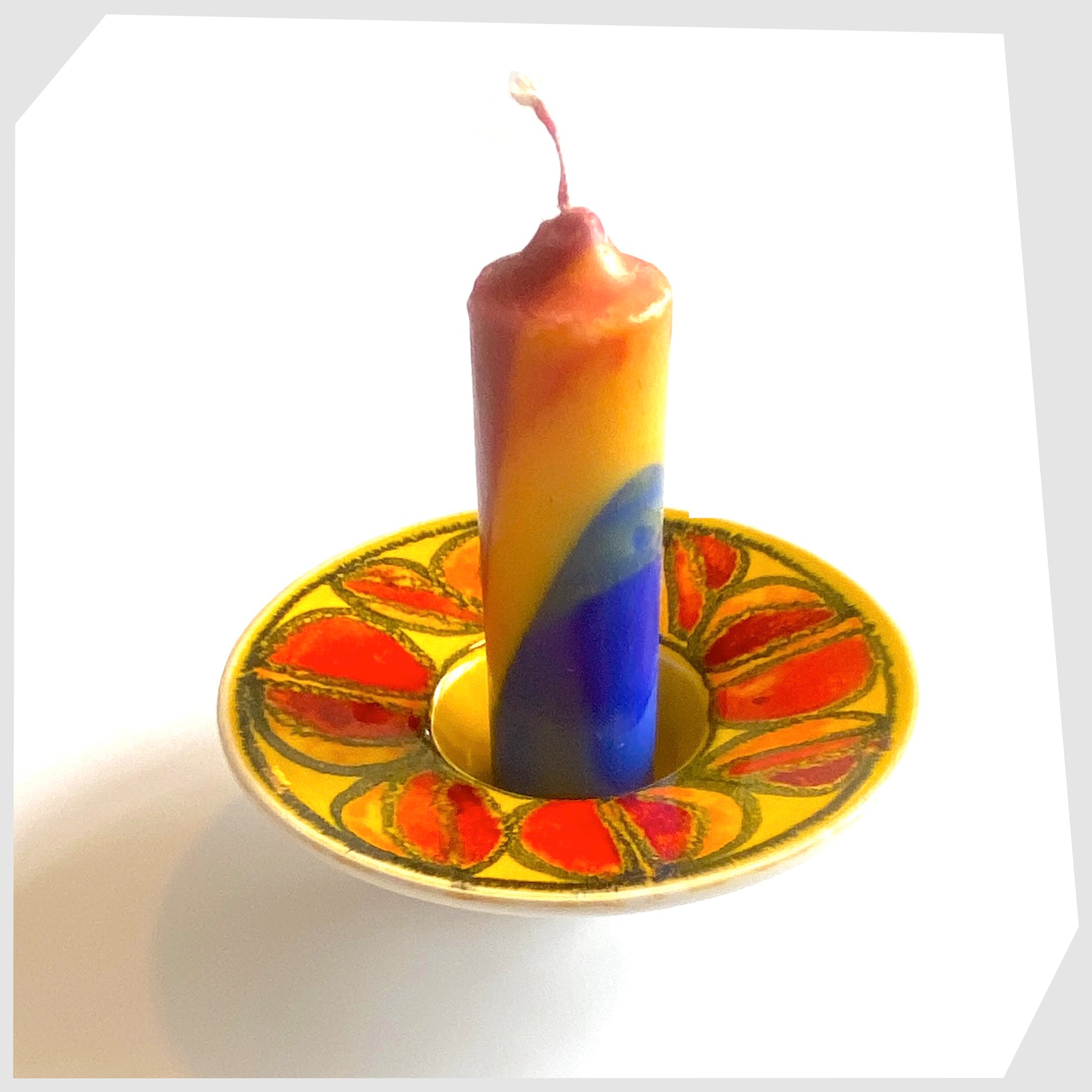 poole pottery delphis candleholder in a vivid yellow glaze with circular forms of red and orange, displayed with a pillar candle