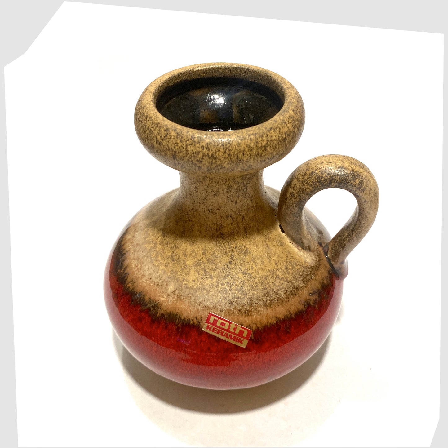 top rim of the roth keramik vase with curved handle with a central stripe of volcanic red glaze
