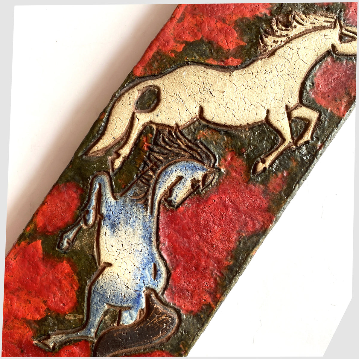 Close up of the Ruscha Keramik Wall Plaque, designed by Adele Bolz, featuring a pair of horses on a red fat lava glaze, shown on a white background