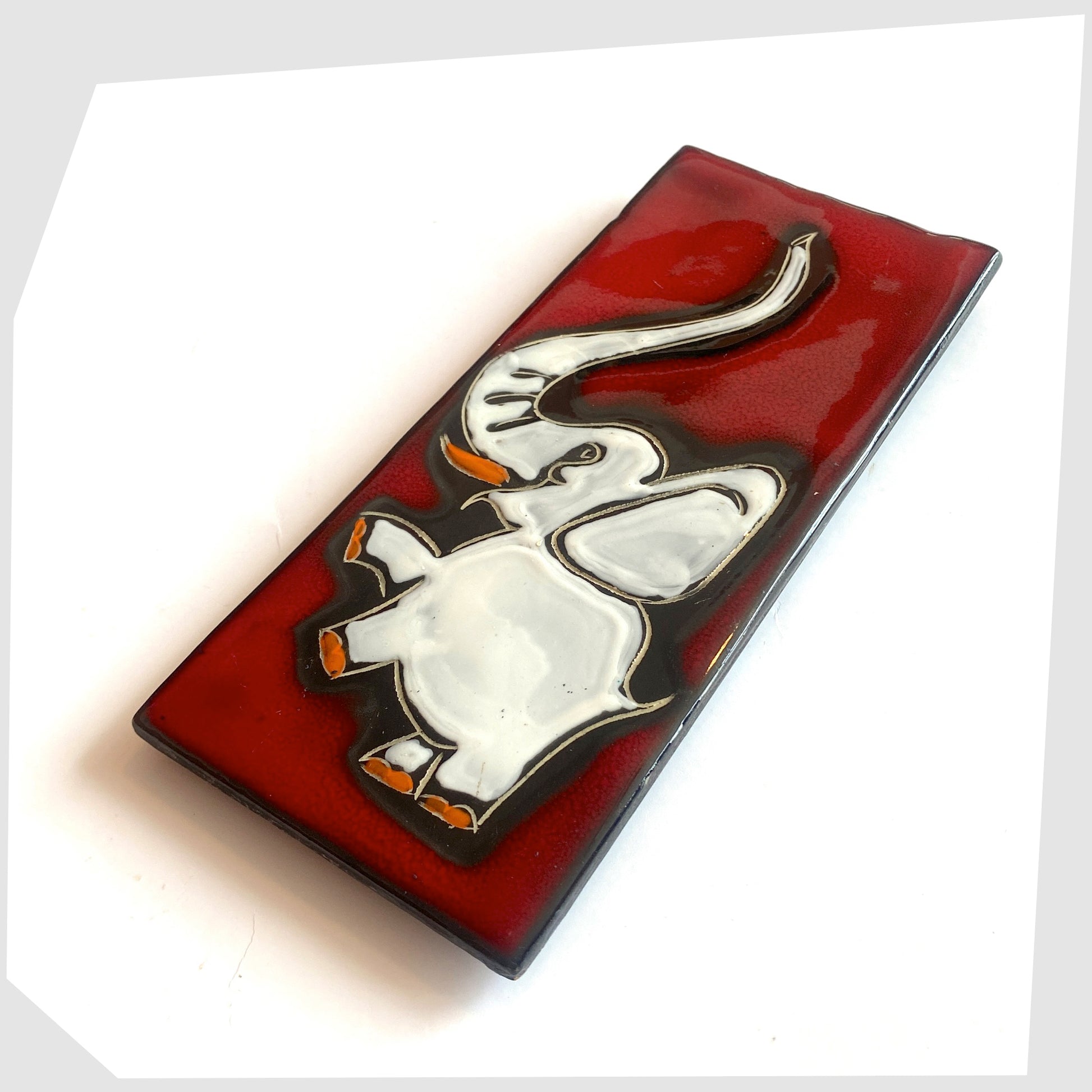 1960s San Marino Pottery Wall Plaque featuring a white elephant with pops of orange on a vivid red glaze, shown on a white background