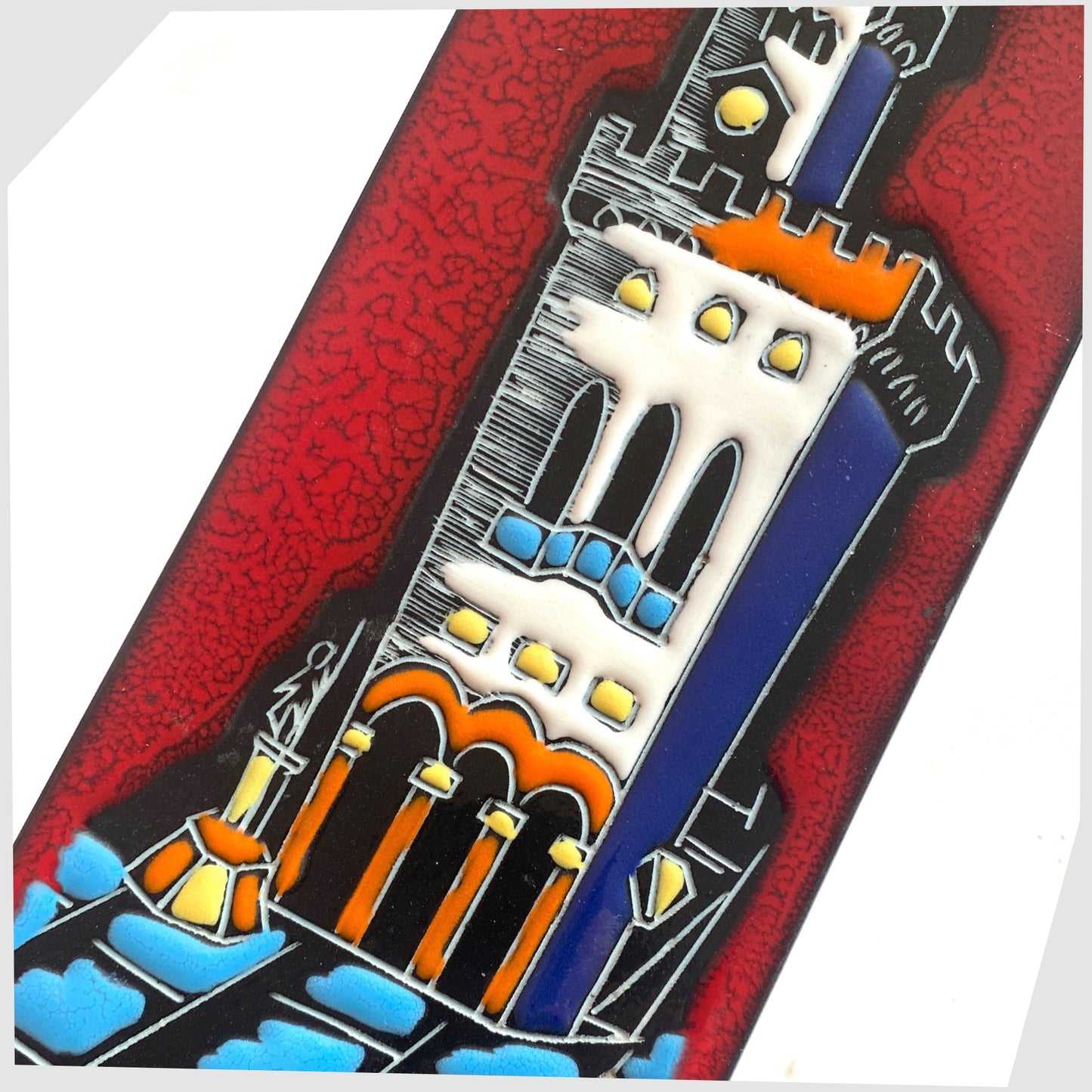 Close up of the San Marino Pottery Wall Plaque featuring a town scene in white, orange and blue on a vibrant red tile, shown on a white background