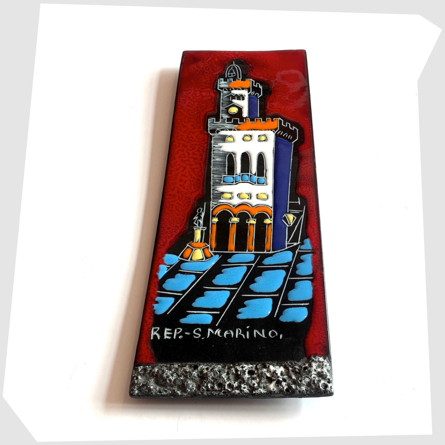 1960s San Marino Pottery Wall Plaque featuring a town scene in white, orange and blue on a vibrant red tile, shown on a white background