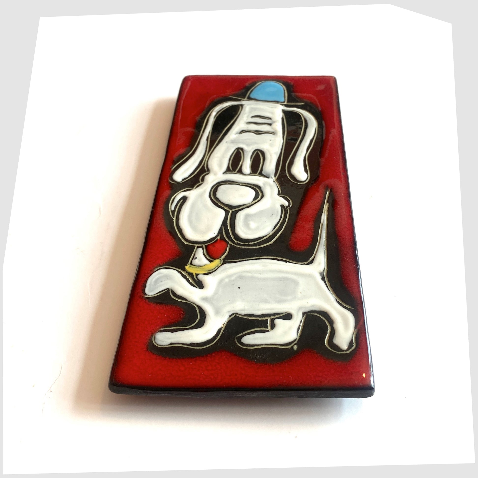 1960s San Marino Pottery Wall Plaque featuring a white dog in a blue hat on a vibrant red glaze, shown on a white background