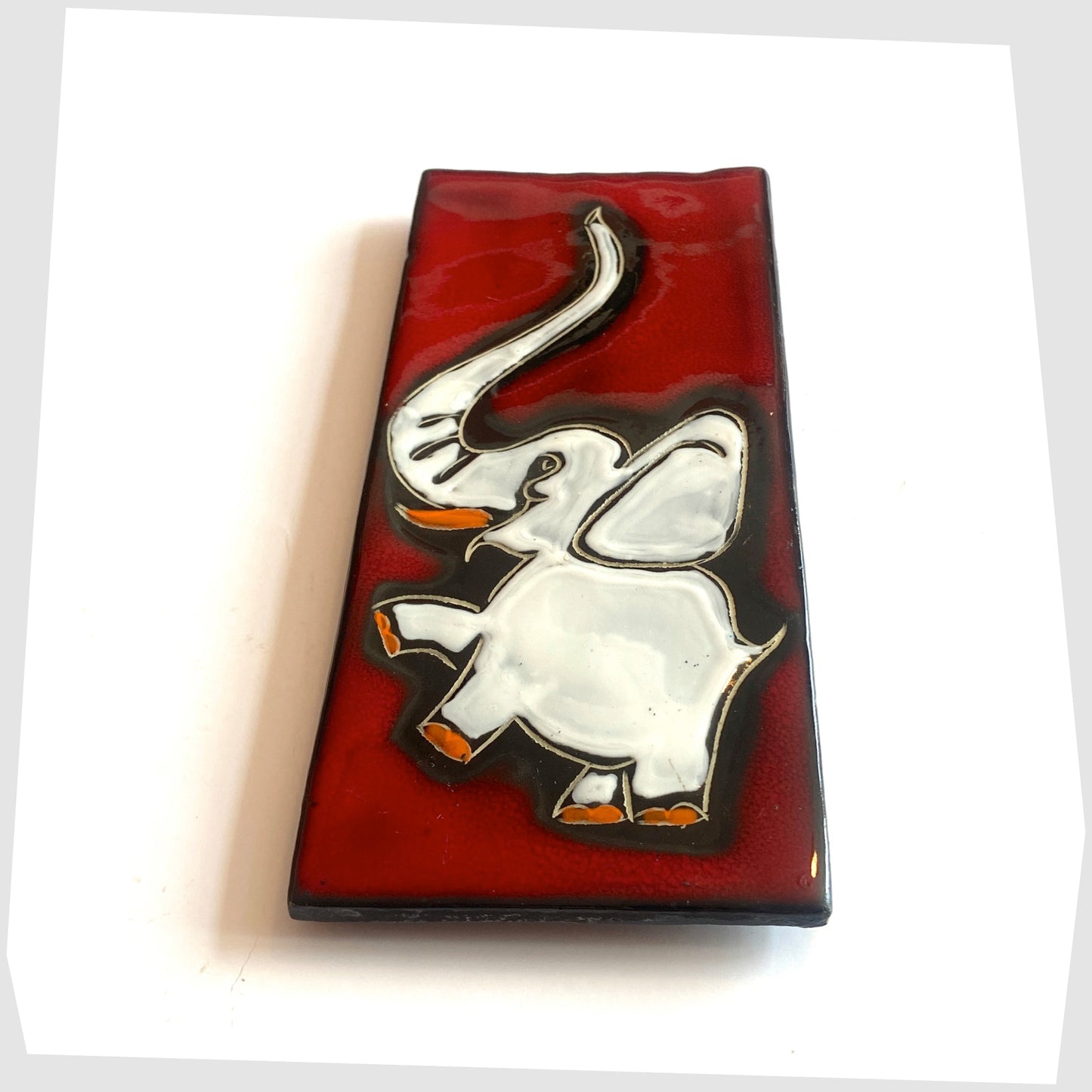 Vintage San Marino Pottery Wall Plaque featuring a white elephant with pops of orange on a vivid red glaze, shown on a white background
