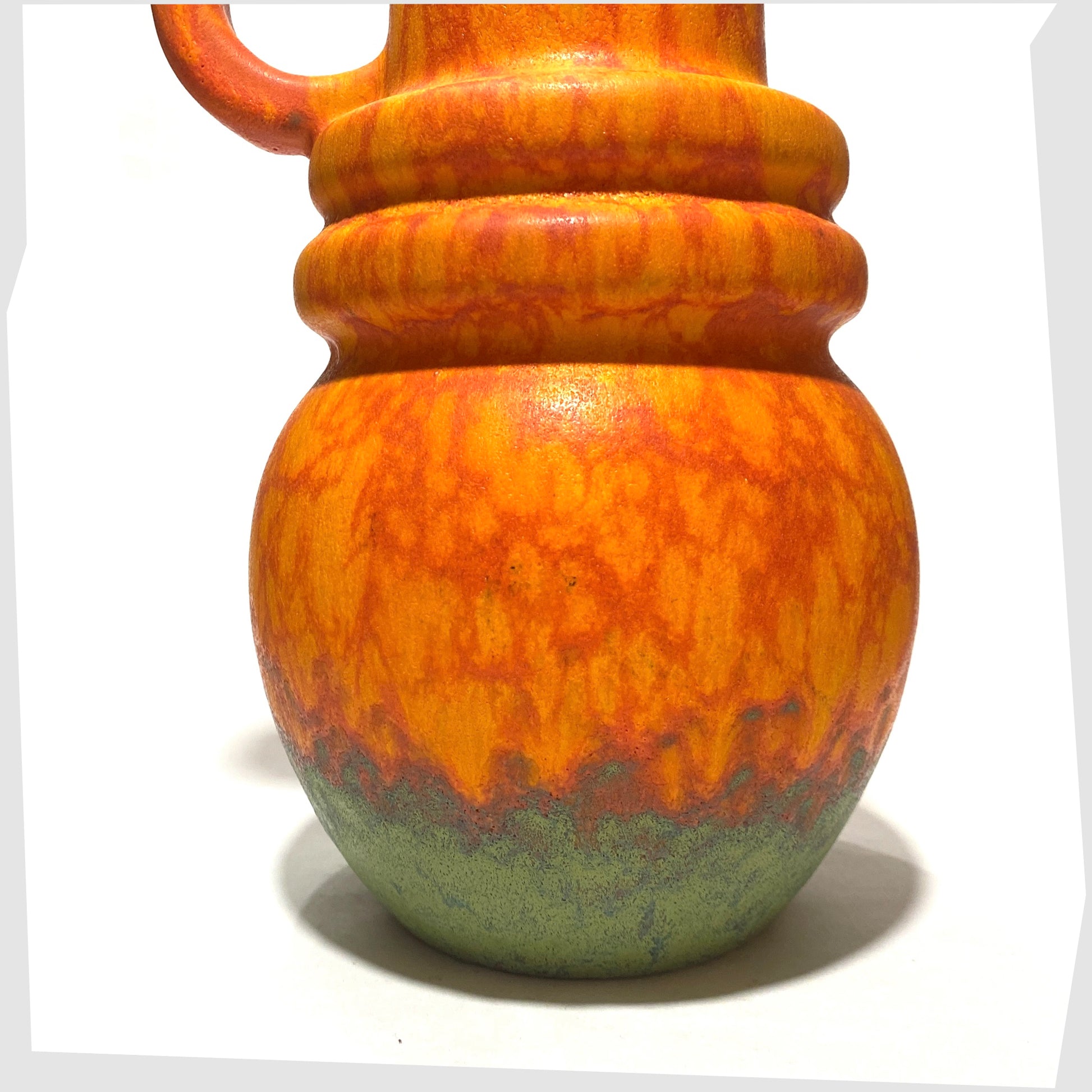 ball-shaped base of the scheurich keramik 428-26 vase finished in a volcanic orange glaze with vivid matte green