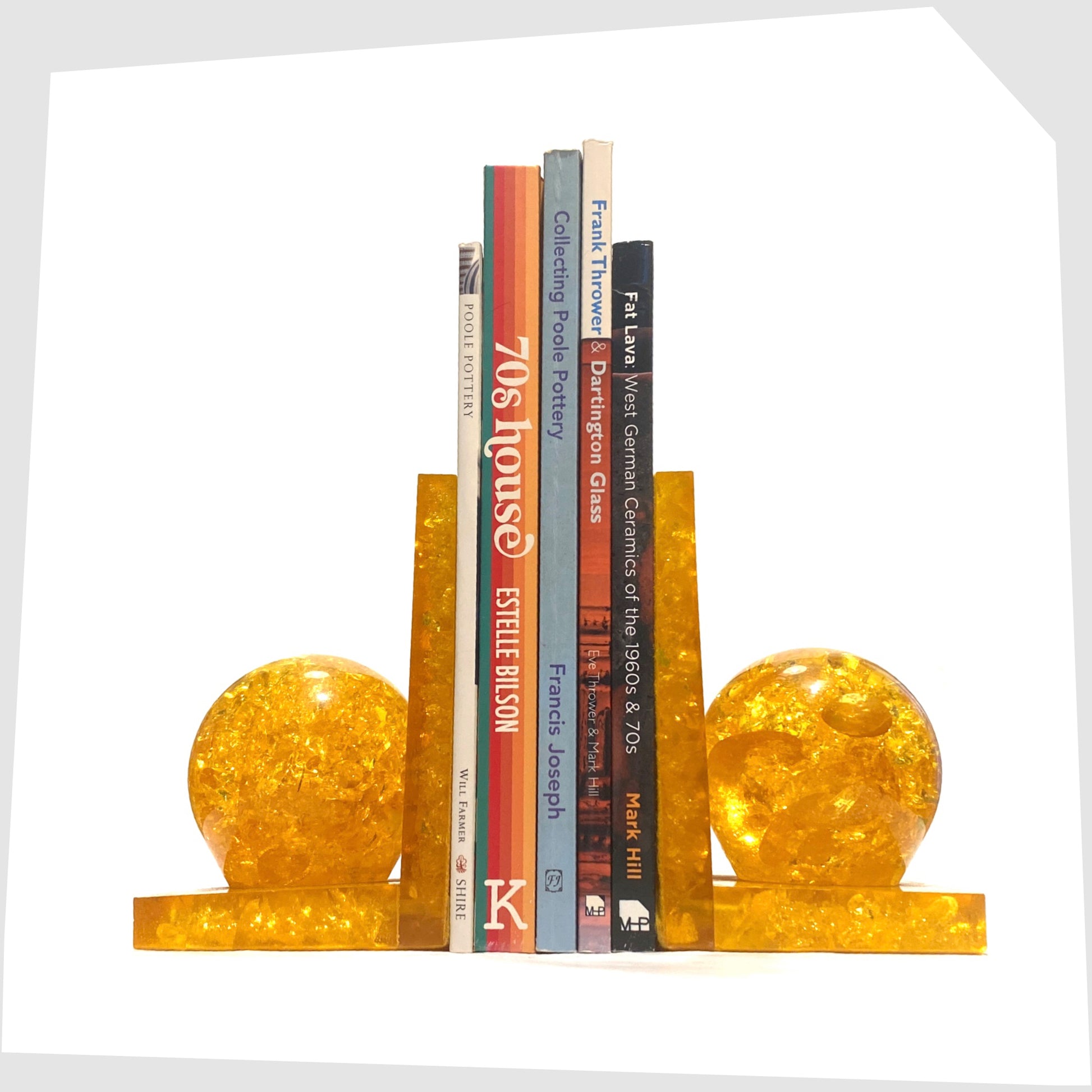 Pair of Shattaline Bookends in orange resin, shown with a selection of books