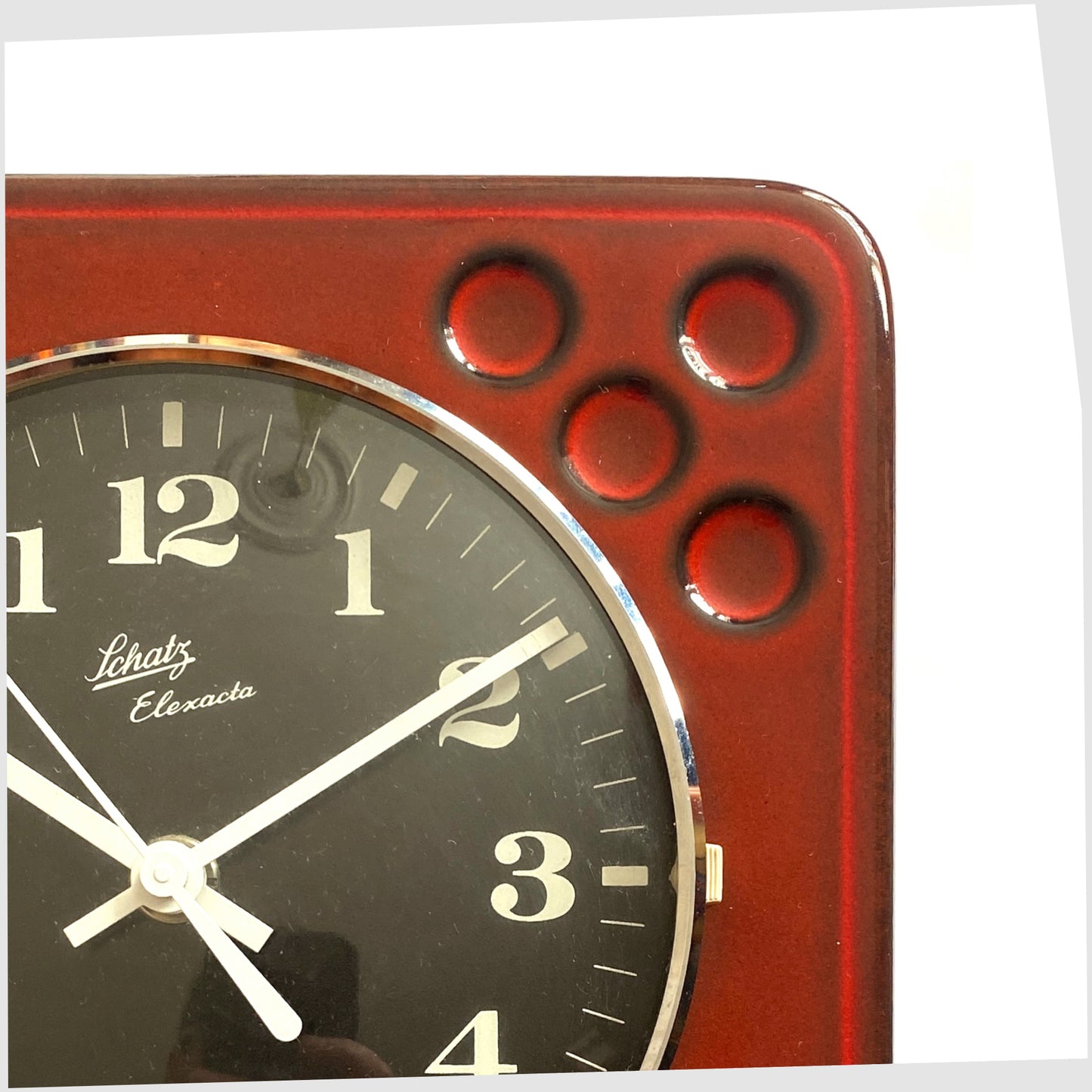 close up of the west german pottery wall clock made of rich red ceramic with black and white dial