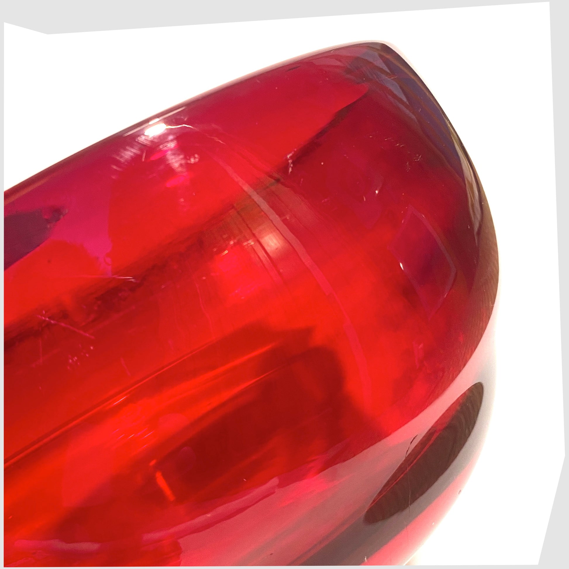 Close up of the side of the Whitefriars Glass Optical Bowl in ruby red glass, shown on a white background